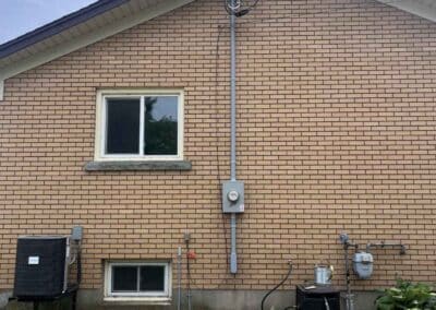 Exterior 200A overhead service installation with new mast, meter base, and conduit upgrade on a brick home in Niagara by Peak 2 Peak Electric.